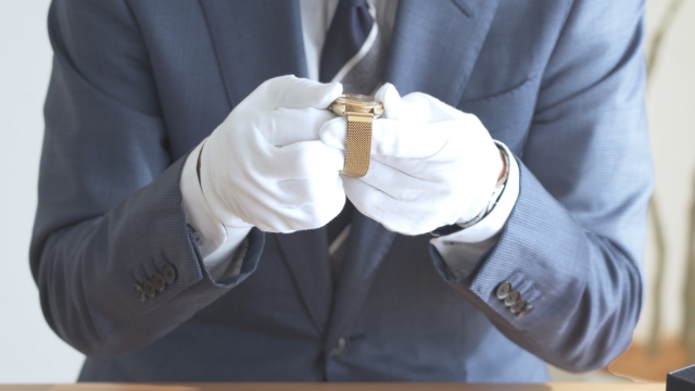金の時計を買取査定する男性