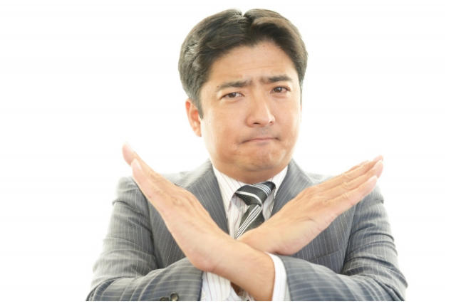 手をバツにしてNGを示す男性